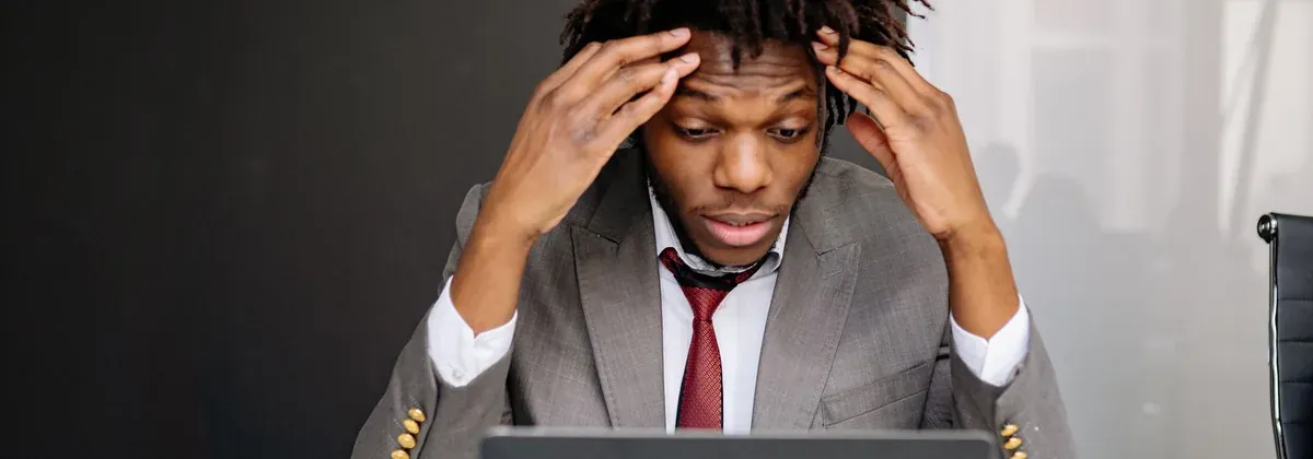 Frustrierter Mann mit den Händen am Kopf vor dem Laptop – eine langsame Website Ladezeit kostet Betriebe täglich Kunden und Aufträge